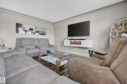 Wood-finish flooring, light gray walls, white ceiling, and a wall-mounted media console with an integrated electric fireplace - 