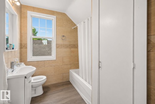 Bathroom featuring a white vanity with integrated sink, white toilet, and a bathtub with shower - 9124 119 Avenue Nw, Edmonton, AB - Indoor Photo Showing Bathroom