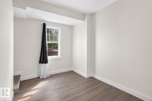 Room featuring wood-finish flooring, white baseboards, a double-hung window, and light-colored walls - 9124 119 Avenue Nw, Edmonton, AB - Indoor Photo Showing Other Room