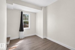 Room featuring wood-finish flooring, white baseboards, a double-hung window, and light-colored walls - 