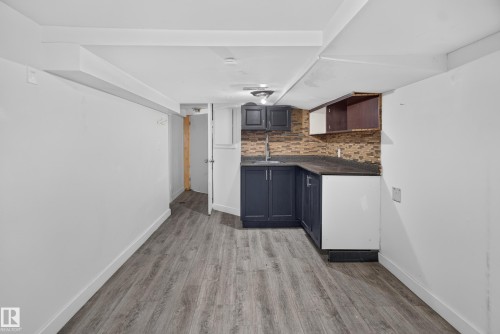 Kitchenette featuring dark cabinetry, mosaic tile backsplash, stainless steel sink, and dark countertops - 9124 119 Avenue Nw, Edmonton, AB - Indoor