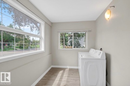 Laundry area featuring wood-finish flooring, light gray walls, and white trim - 9124 119 Avenue Nw, Edmonton, AB - Indoor Photo Showing Laundry Room