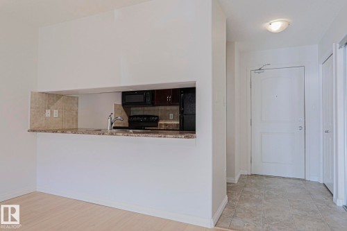 Kitchen pass-through with a stone-finish countertop and tile backsplash - #108 1204 156 St Nw, Edmonton, AB 