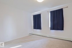 Carpeted flooring with white wall finishes, two windows, and baseboard heating - 