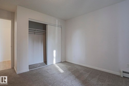Neutral gray carpeting, white walls, and a built-in closet with sliding doors - #108 1204 156 St Nw, Edmonton, AB 