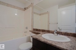 Built-in bathtub with shower, tiled surround, vanity with an integrated sink, and a large wall mirror - 