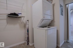 Stacked laundry appliances, wire shelving, and tiled flooring - 
