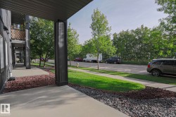 Exterior corridor with concrete walkway, black siding, and decorative gravel landscaping - 