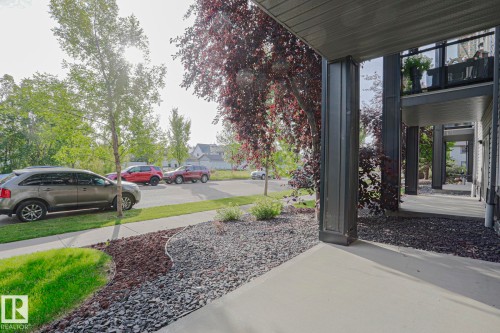 Concrete walkway leading to a covered porch with dark gray support columns - #108 1204 156 St Nw, Edmonton, AB 