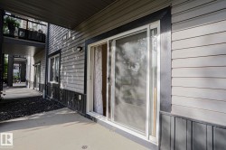 Patio with a concrete surface, featuring a sliding glass door, horizontal siding, and a wall-mounted light fixture - 