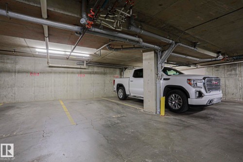 Underground parking space featuring a concrete floor, concrete walls, and overhead lighting - #108 1204 156 St Nw, Edmonton, AB 