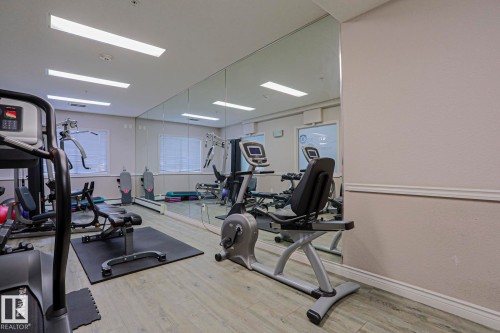 Fitness room featuring full-wall mirrors, wood-finish flooring, and recessed lighting - #108 1204 156 St Nw, Edmonton, AB 