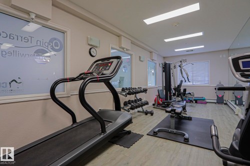 Fitness center with multiple exercise machines, weight rack, and wood-finish flooring - #108 1204 156 St Nw, Edmonton, AB 