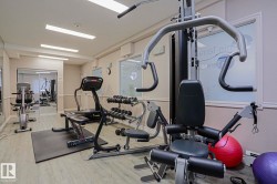 Fitness center featuring multiple exercise machines, weight training equipment, and wood-finish flooring - 