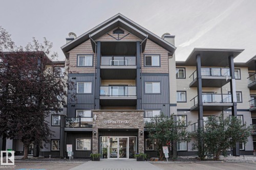 Contemporary multi-story building featuring stone veneer accents, multiple balconies with glass railings, and a prominent main entrance - #108 1204 156 St Nw, Edmonton, AB 