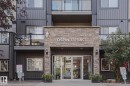 Stone-clad entrance with glass double doors, featuring integrated exterior lighting and a building nameplate - #108 1204 156 St Nw, Edmonton, AB 