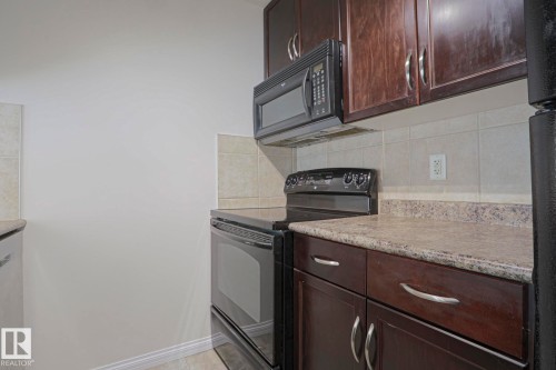Dark wood-finish cabinetry, light-toned countertops, and a tile backsplash - #108 1204 156 St Nw, Edmonton, AB 