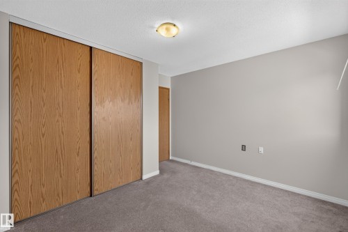 Wood-finish sliding closet doors, wall-to-wall carpeting, light neutral wall paint, and a flush mount ceiling light - 17749 95 Street Nw, Edmonton, AB 