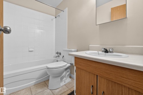 White tiled shower surround, integrated tub, light wood-finish vanity, integrated sink, and wall-mounted mirror - 17749 95 Street Nw, Edmonton, AB 