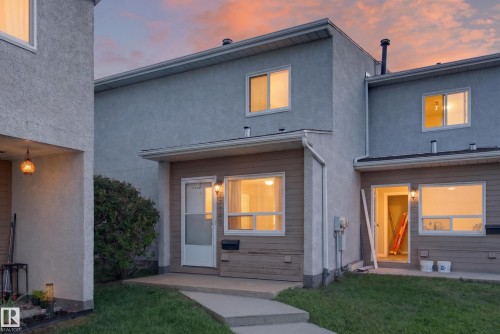 Multi-story townhouse exterior featuring a stucco and siding facade, white window frames, and a concrete walkway - 17749 95 Street Nw, Edmonton, AB 