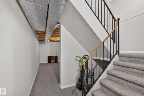 Carpeted staircase with black metal balusters and a brass-tone handrail - 17749 95 Street Nw, Edmonton, AB 