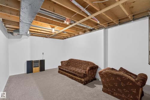 Carpeted floor with exposed ceiling joists and ductwork, featuring white painted walls and a structural column - 17749 95 Street Nw, Edmonton, AB 