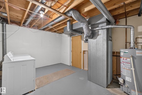 Unfinished basement with exposed ceiling joists, painted concrete flooring, and a water heater - 17749 95 Street Nw, Edmonton, AB 