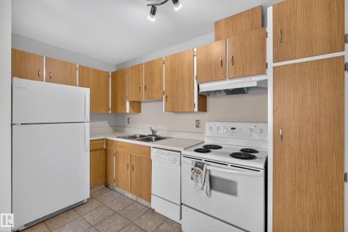 Kitchen featuring wood-finish cabinetry, white appliances, and track lighting - 17749 95 Street Nw, Edmonton, AB 