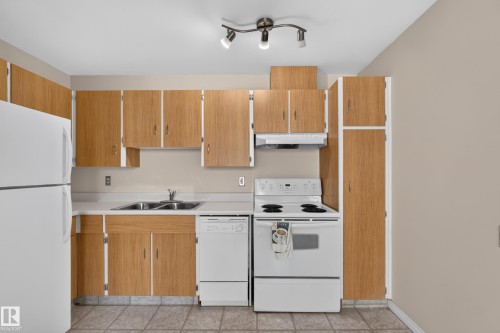 Kitchen featuring wood-finish cabinetry, white appliances, dual stainless steel sink, and track lighting - 17749 95 Street Nw, Edmonton, AB 