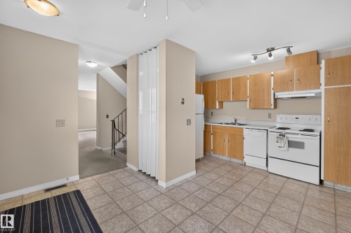 Kitchen featuring wood-finish cabinetry, white appliances, and tiled flooring - 17749 95 Street Nw, Edmonton, AB 