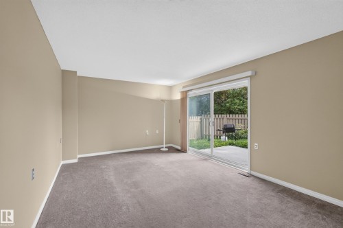 Sliding glass door leading to a concrete patio, wood privacy fence, and a green space - 17749 95 Street Nw, Edmonton, AB 