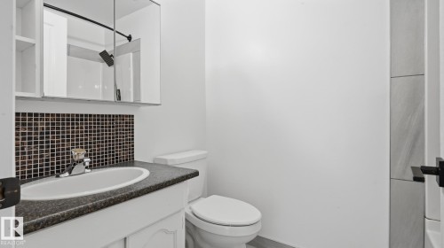 Vanity with dark speckled countertop, mosaic tile backsplash, and mirrored medicine cabinet - 12208 146 Avenue Nw, Edmonton, AB 