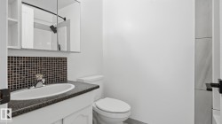 Vanity with dark speckled countertop, mosaic tile backsplash, and mirrored medicine cabinet - 