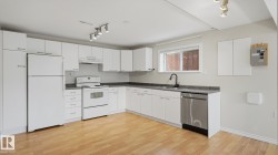 Kitchen featuring wood-finish flooring, white cabinetry, integrated range with overhead hood, and a stainless steel dishwasher - 
