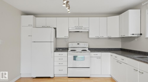 Kitchen featuring white cabinetry, dark speckled countertops, white appliances, track lighting, and wood-finish flooring - 12208 146 Avenue Nw, Edmonton, AB 