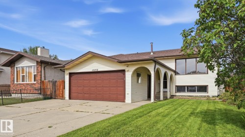 Exterior featuring a two-car garage, archway-covered entrance, and a well-maintained lawn - 12208 146 Avenue Nw, Edmonton, AB 