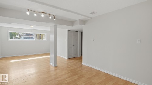Hardwood-finish flooring with a horizontal window, track lighting, and a bi-fold closet door - 12208 146 Avenue Nw, Edmonton, AB 