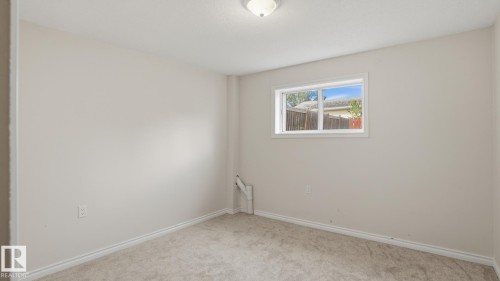 Neutral-toned walls, light-colored carpeting, a single window, and a ceiling-mounted light fixture - 12208 146 Avenue Nw, Edmonton, AB 