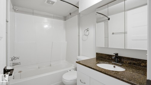 Tub-shower combination with white surround, vanity with granite-finish countertop, undermount sink, black-finish faucet, and mirrored medicine cabinet - 12208 146 Avenue Nw, Edmonton, AB 