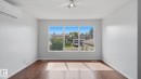 Expansive room featuring rich wood-finish flooring, a wall-mounted mini-split air conditioning unit, and a ceiling fan with integrated lighting - 12208 146 Avenue Nw, Edmonton, AB 