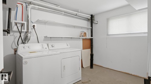 Dedicated laundry area with a washer and dryer, fixed utility shelving, and a window with blinds - 12208 146 Avenue Nw, Edmonton, AB 