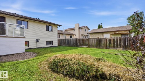 Expansive green space, privacy fencing, upper-level deck with glass railing, lower-level patio with paver stones, and exterior siding - 12208 146 Avenue Nw, Edmonton, AB 