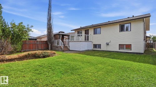 Expansive backyard featuring a manicured lawn, a raised deck with glass railings, and a gazebo - 12208 146 Avenue Nw, Edmonton, AB 