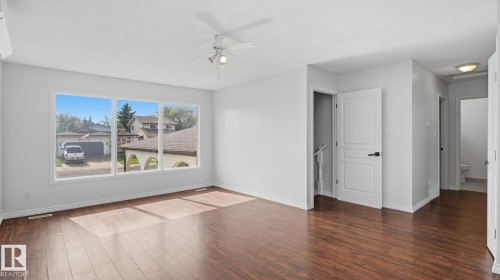 Expansive room featuring wood-finish flooring, a multi-pane window, and a ceiling fan with integrated lighting - 12208 146 Avenue Nw, Edmonton, AB 