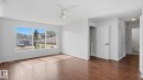 Expansive room featuring wood-finish flooring, a multi-pane window, and a ceiling fan with integrated lighting - 12208 146 Avenue Nw, Edmonton, AB 