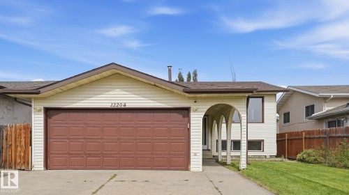Attached two-car garage with a brown panel door - 12208 146 Avenue Nw, Edmonton, AB 