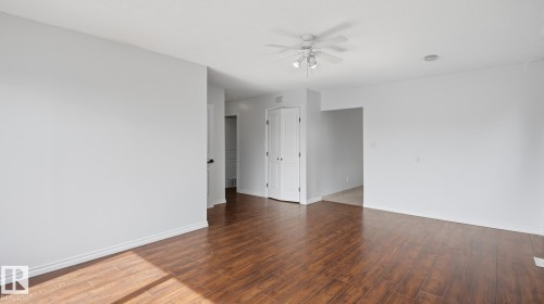 Wood-finish flooring, white walls, white ceiling fan, white bi-fold door, and a threshold to an adjacent room - 12208 146 Avenue Nw, Edmonton, AB 