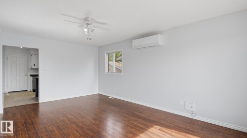 Wood-finish flooring, ceiling fan with integrated lighting, wall-mounted air conditioning unit, and white baseboards - 12208 146 Avenue Nw, Edmonton, AB 