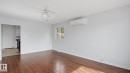 Wood-finish flooring, ceiling fan with integrated lighting, wall-mounted air conditioning unit, and white baseboards - 12208 146 Avenue Nw, Edmonton, AB 