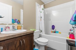 Full bathroom featuring a single vanity with wood-finish cabinetry, a white basin, and a chrome faucet - 